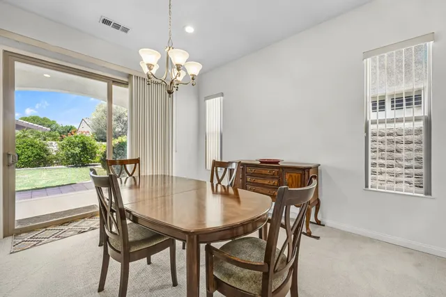 a view of a dining room with furniture a chandelier and large windows