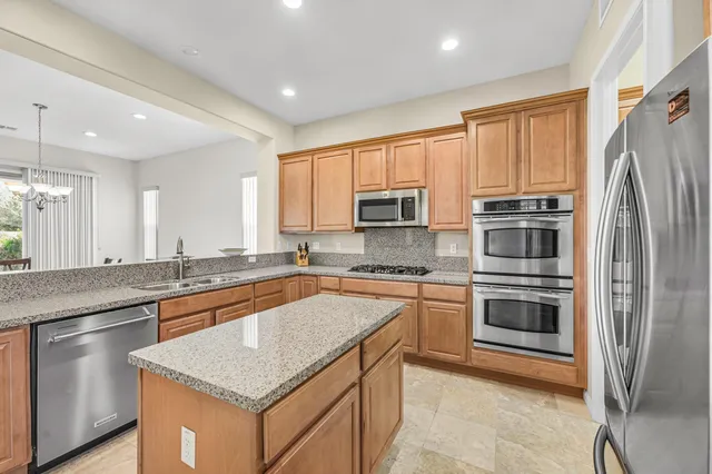 a kitchen with stainless steel appliances granite countertop a stove top oven a sink and a refrigerator