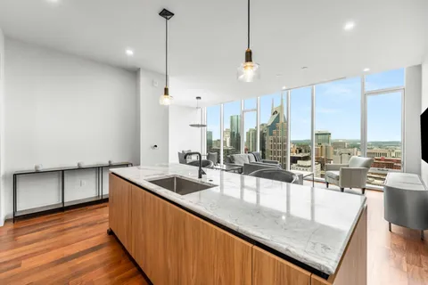 a kitchen with stainless steel appliances granite countertop a sink a counter top space and living room view