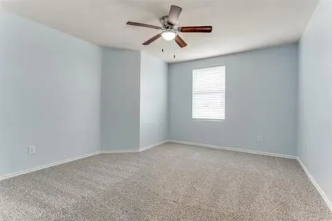 an empty room with a window and a fan