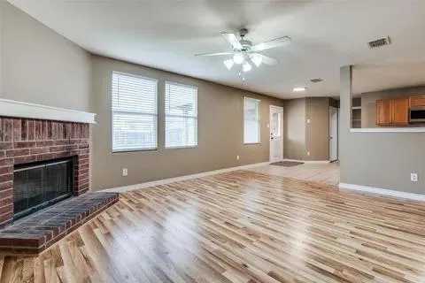 a view of an empty room with window and wooden floor