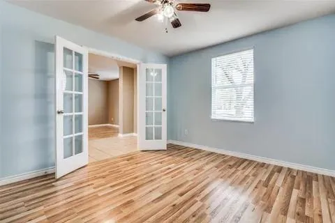 a view of an empty room with wooden floor and a window