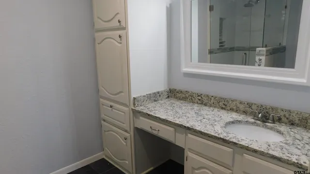 a bathroom with a granite countertop sink and a window