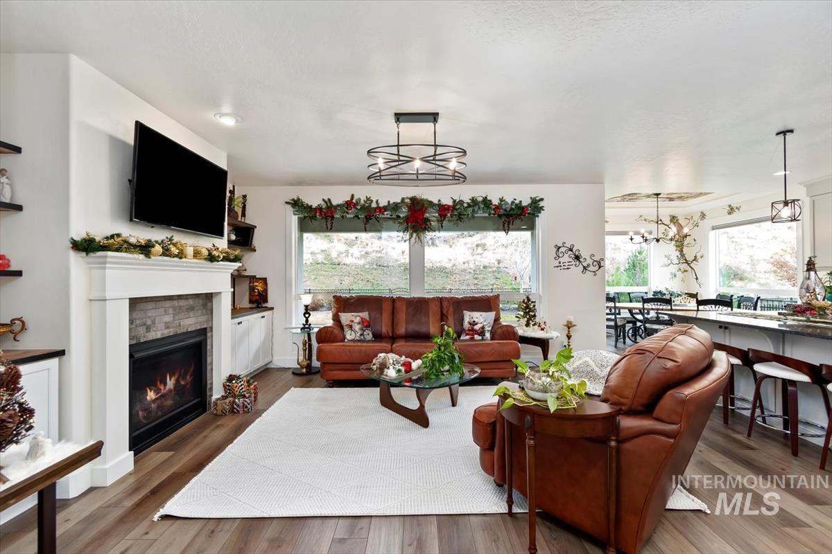 20530 North Shepherds Pie Way Boise, ID 83714 - Photo 2 of 47 Living area with a glass covered fireplace, wood finished floors, and a chandelier