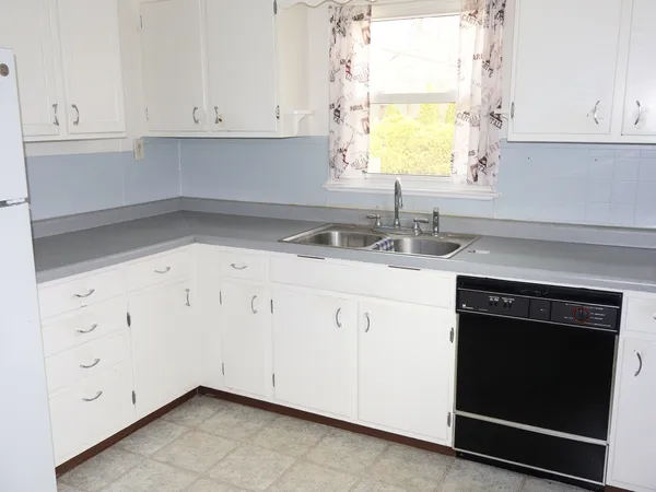 a kitchen with granite countertop white cabinets white appliances and a sink