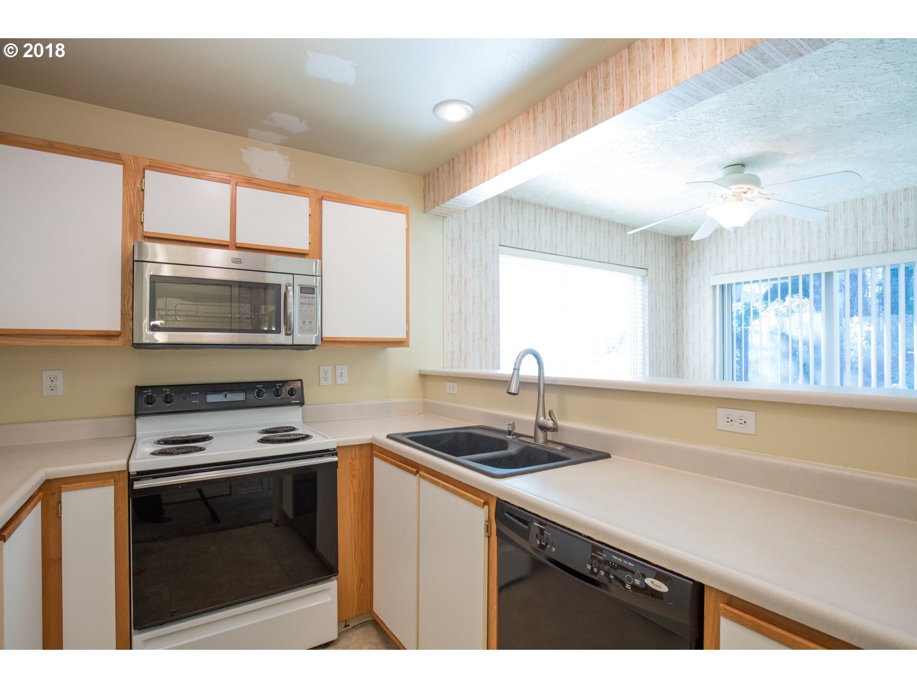 7123 Southwest Sagert Street, Unit 101 Tualatin, OR 97062 - Photo 3 of 24 a kitchen with granite countertop a stove a sink and a microwave