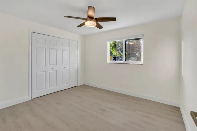 a view of an empty room with wooden floor and windows