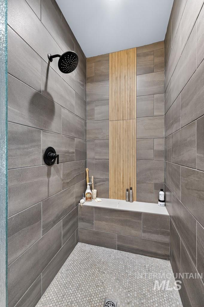 13800 Raptor Loop McCall, ID 83638 - Photo 19 of 34 Shower stall featuring dark gray rectangular wall tiling, a light wood-finish accent wall, and a built-in bench