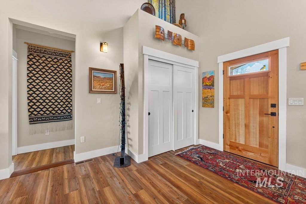 13800 Raptor Loop McCall, ID 83638 - Photo 2 of 34 Inviting entryway featuring wood-finish flooring, a solid wood front door with transom window, and a built-in coat closet with white sliding doors