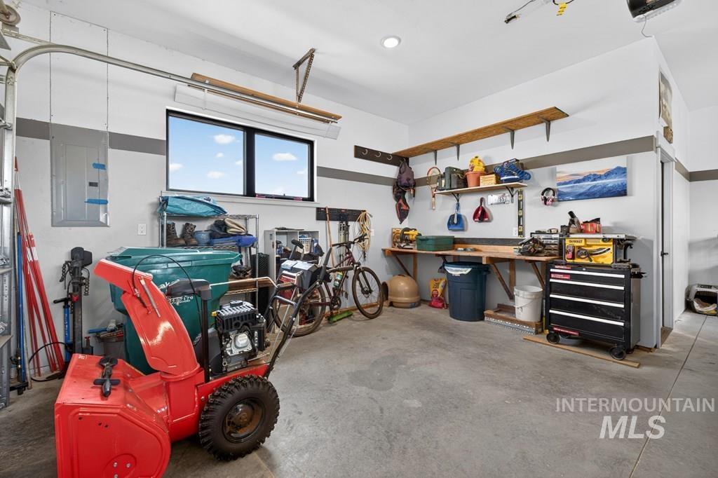 13800 Raptor Loop McCall, ID 83638 - Photo 29 of 34 Spacious garage featuring a concrete floor, built-in workbench, wall-mounted shelving, overhead lighting, and a horizontal window