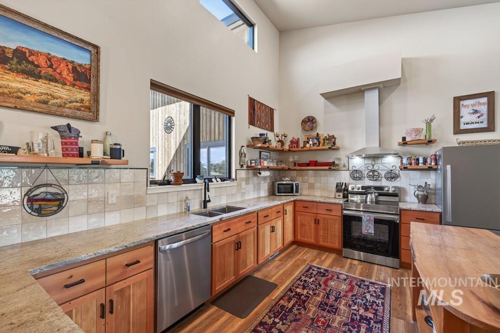 13800 Raptor Loop McCall, ID 83638 - Photo 6 of 34 Kitchen featuring vaulted ceilings with skylight, wood-finish flooring, light wood cabinetry, stone countertops, and stainless steel appliances