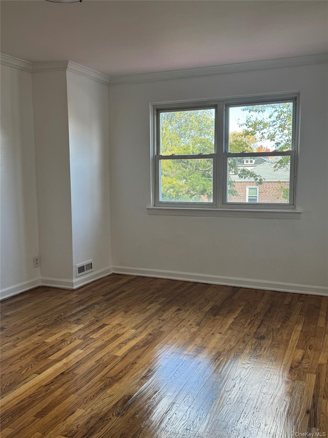 1574 Paulding Avenue, Unit 2 Bronx, NY 10462 - Photo 9 of 25 a view of an empty room with wooden floor and a window