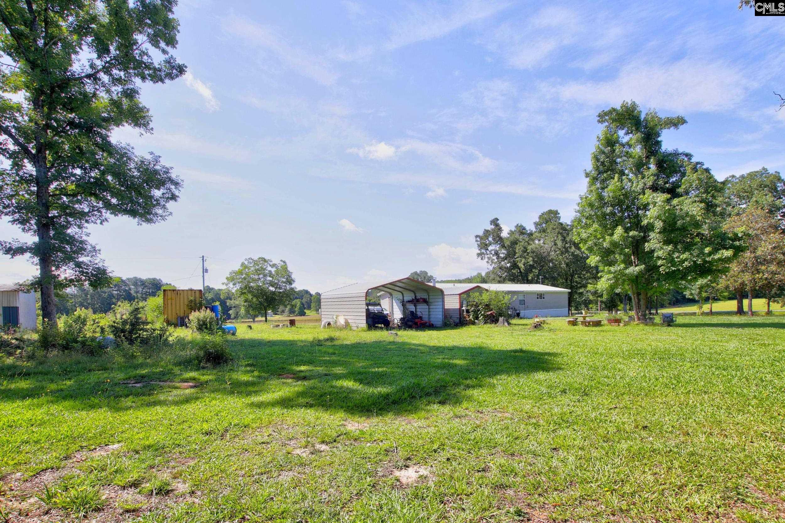 3140 Highway 702 Chappells, SC 29037 - Photo 19 of 39 a view of a house with a big yard and potted plants and large trees