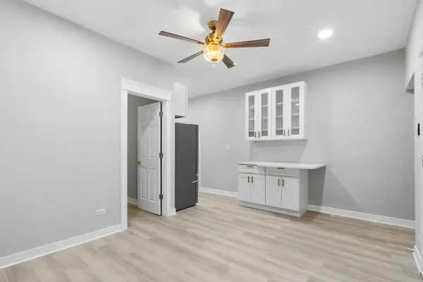 an empty room with a kitchen and a ceiling fan