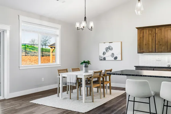 a kitchen with kitchen island granite countertop a table chairs microwave and refrigerator