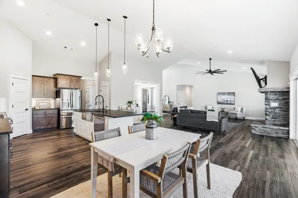 a kitchen with stainless steel appliances granite countertop a stove top oven a refrigerator a sink and chairs with wooden floor