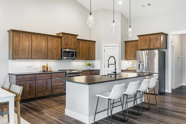a kitchen with kitchen island granite countertop a stove top oven a sink dishwasher a dining table and chairs with wooden floor