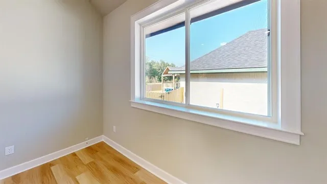 an empty room with wooden floor cabinet and windows