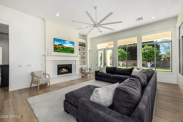 a large white kitchen with kitchen island a stove a sink a refrigerator and white cabinets with wooden floor