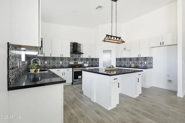 a kitchen with granite countertop a refrigerator a stove a sink and white cabinets