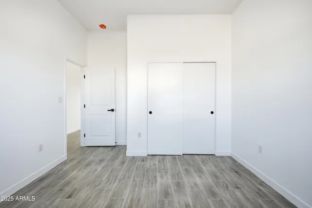 an empty room with wooden floor ceiling fan and window