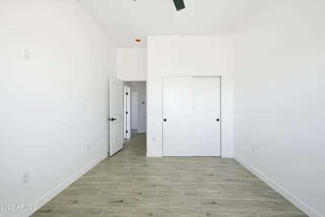 an empty room with a wooden floor and a ceiling fan