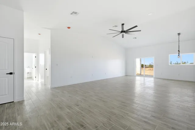 a view of empty room with wooden floor and ceiling fan