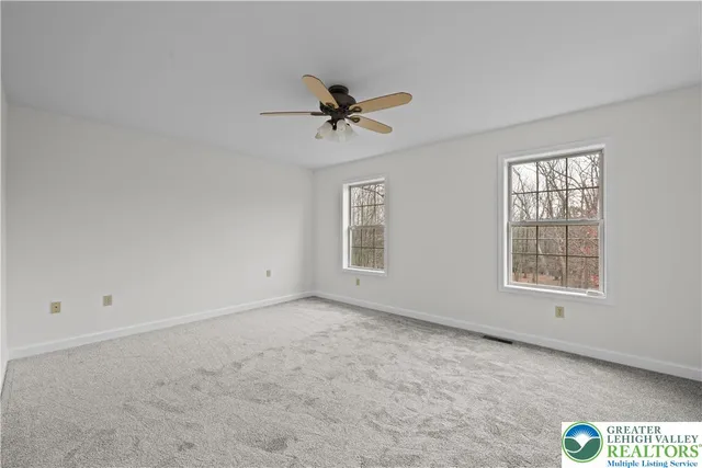 an empty room with windows and fan