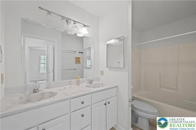 a bathroom with a granite countertop sink a toilet and bathtub