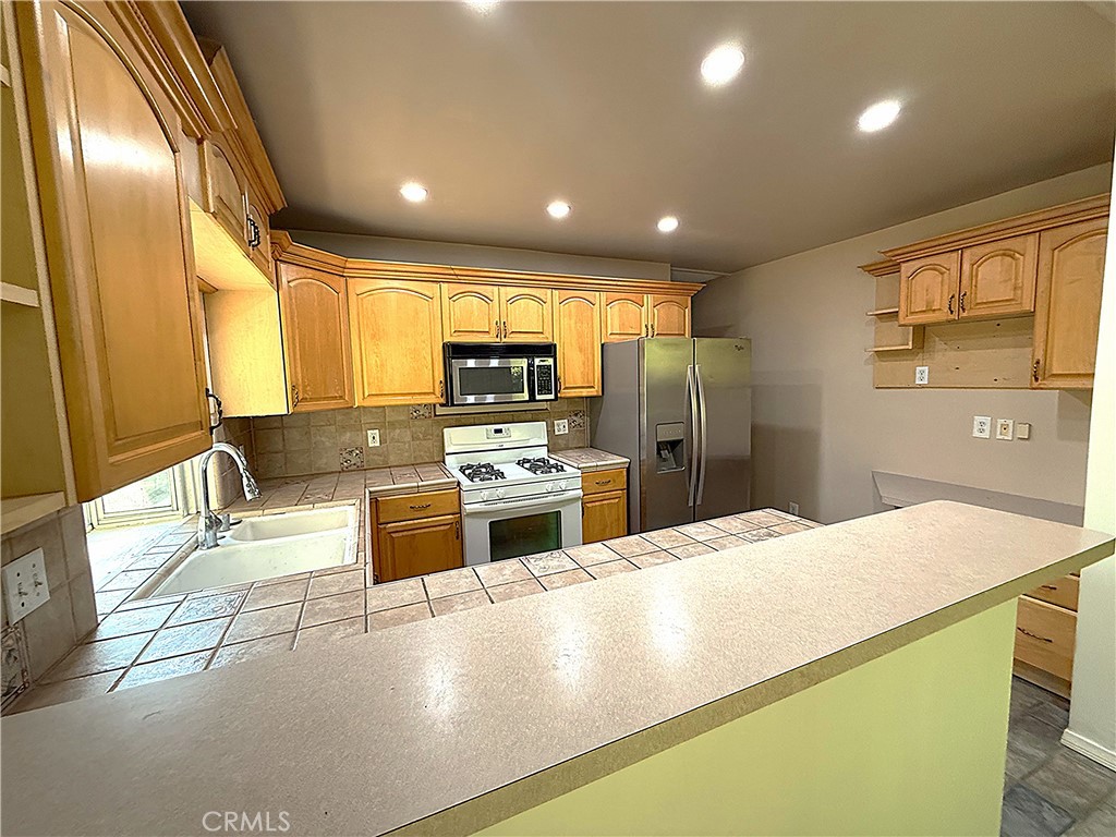 6652 Valmont Street Tujunga, CA 91042 - Photo 4 of 16 a large kitchen with stainless steel appliances a large counter top a stove a chimney a sink and a refrigerator