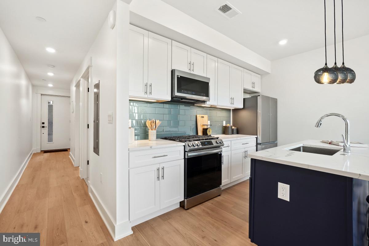 1605 Holbrook Street Northeast, Unit 1 Washington, DC 20002 - Photo 6 of 25 a kitchen with stainless steel appliances a sink dishwasher a refrigerator and a stove with wooden floor