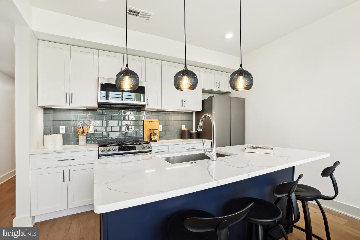 1605 Holbrook Street Northeast, Unit 1 Washington, DC 20002 - Photo 7 of 25 a kitchen with kitchen island stainless steel appliances a dining table a sink and cabinets