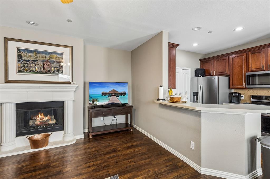 5500 Conch Train Road McKinney, TX 75070 - Photo 10 of 34 a living room with stainless steel appliances furniture a fireplace a flat screen tv and a window