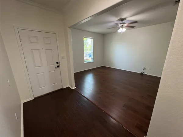 a view of a big room with wooden floor and chandelier fan