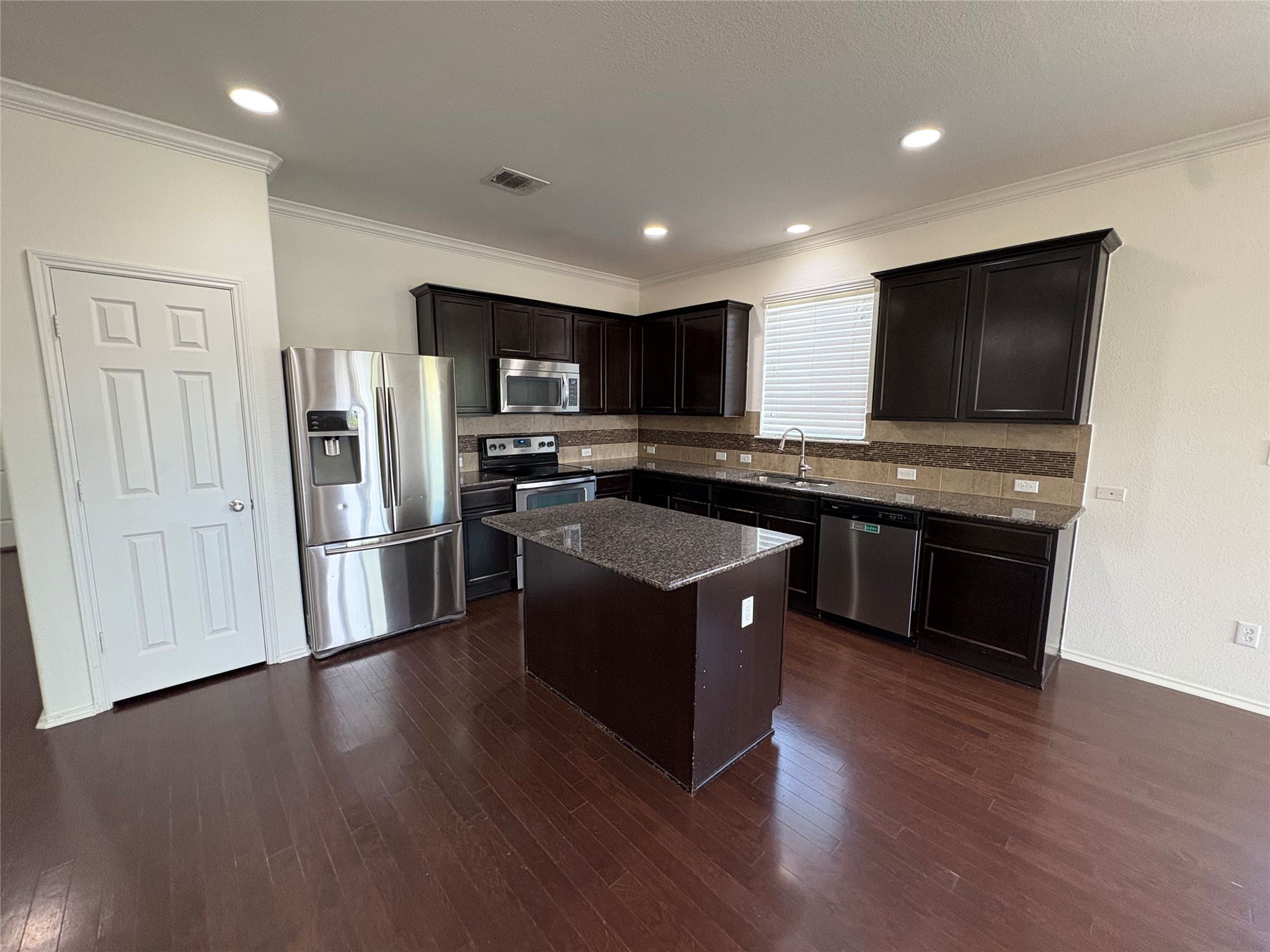 11617 Murron Drive Austin, TX 78754 - Photo 7 of 30 a kitchen with stainless steel appliances granite countertop a stove a sink dishwasher a refrigerator and a microwave oven with wooden floor