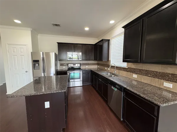 an empty room with wooden floor chandelier fan and windows
