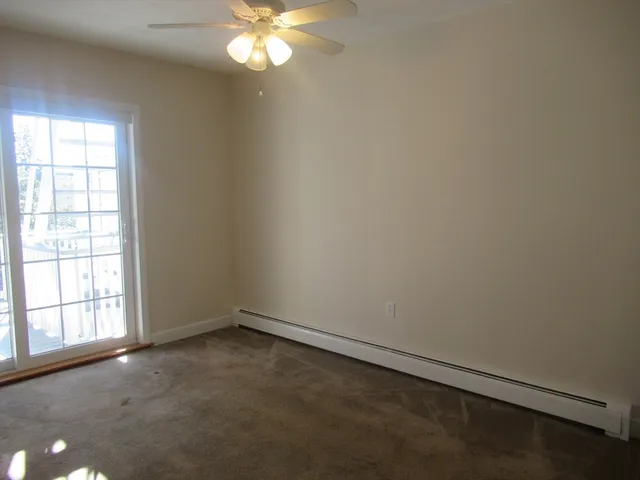 an empty room with windows and chandelier fan