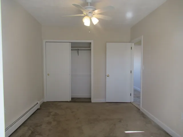 an empty room with closet and a chandelier fan