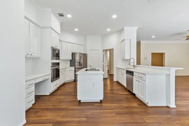 a large kitchen with granite countertop a large counter top space a sink stainless steel appliances and windows