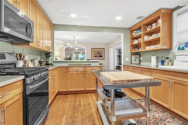 a kitchen with stainless steel appliances granite countertop a stove top oven a sink dishwasher and cabinets with wooden floor