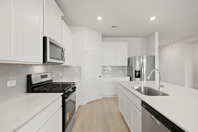 a kitchen that has a sink cabinets counter space and stainless steel appliances