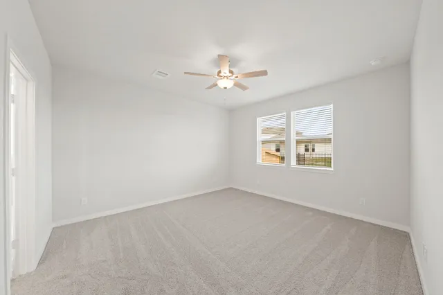 an empty room with windows and ceiling fan