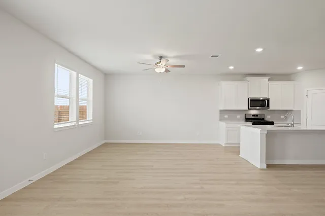 a view of kitchen with sink a microwave and cabinets