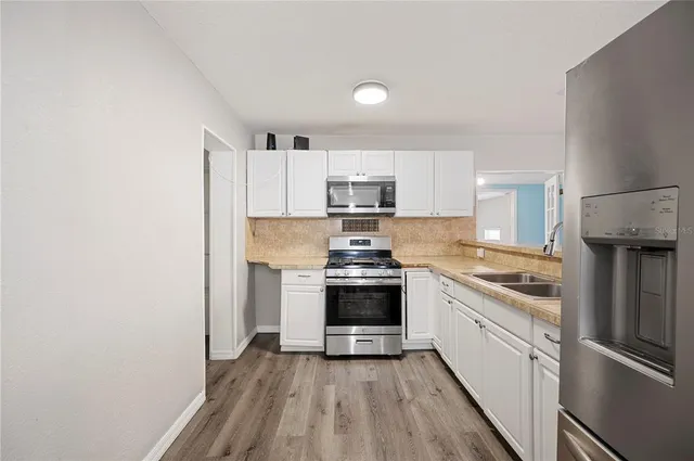 a kitchen with stainless steel appliances granite countertop a stove top oven a sink and a refrigerator