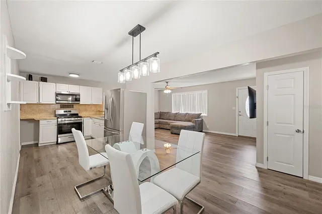 a view of a dining room and livingroom with furniture wooden floor kitchen view and a window