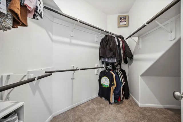 a view of walk in closet with clothes and shoes