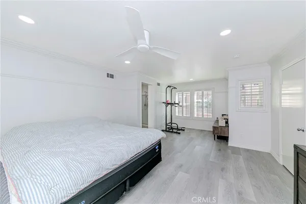 a spacious bedroom with a bed and wooden floor