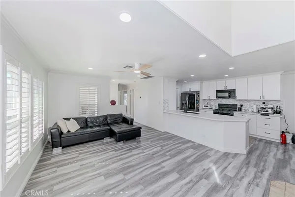 a large living room with stainless steel appliances granite countertop couches a flat screen tv and fireplace