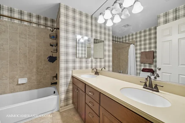 a bathroom with a sink double vanity granite tub shower and a mirror