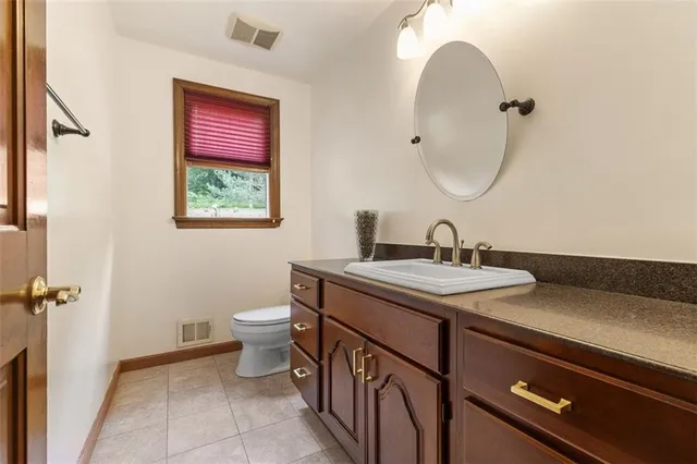 a bathroom with a granite countertop sink a toilet and a mirror